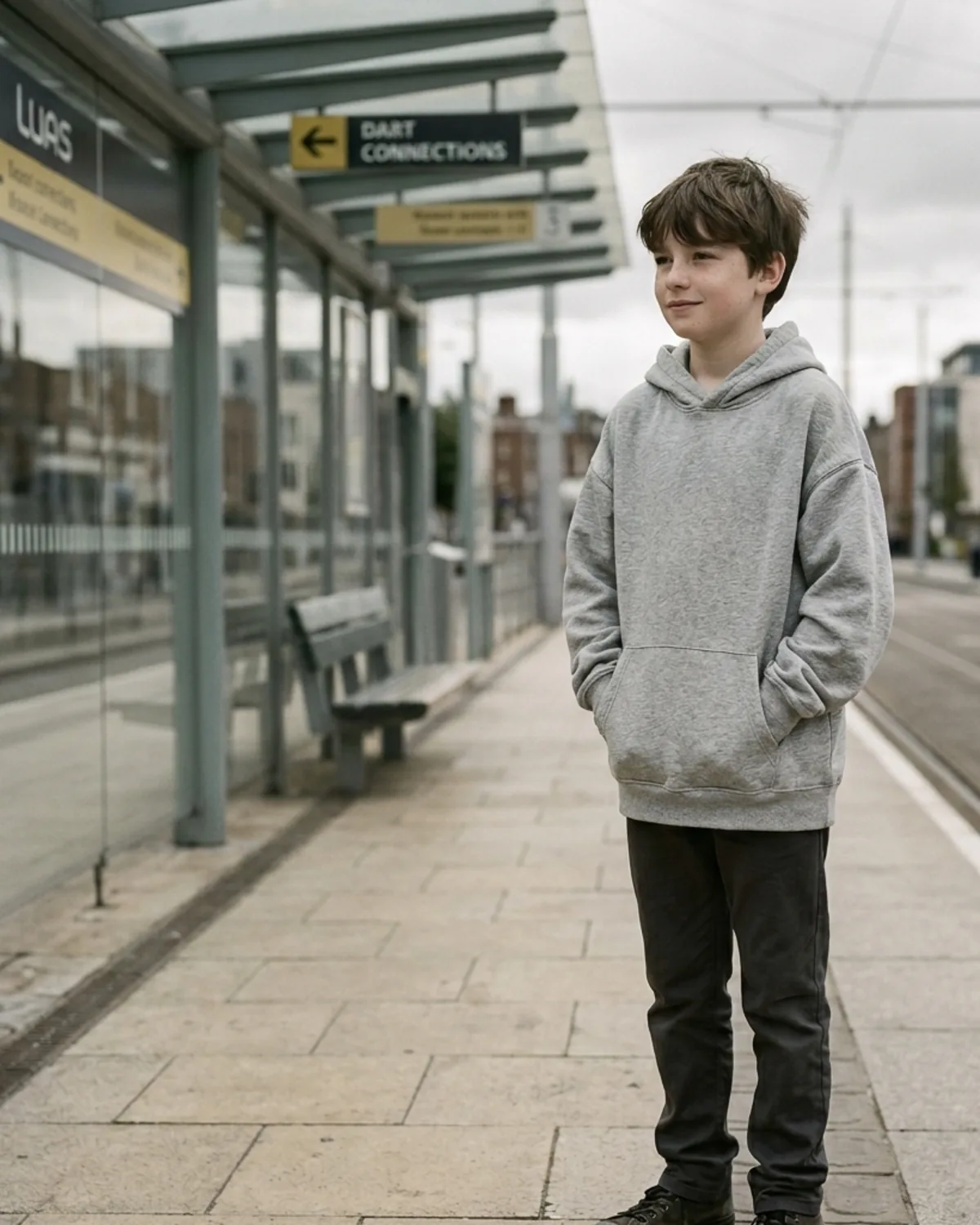 Boy in heather grey Cosi hoodie on a tram platform.